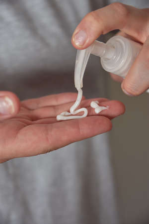 Woman hand using dispenser to apply cream on skin with Psoriasisの写真素材