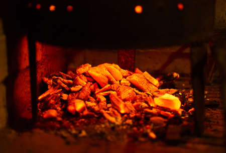 Red hot coals burning ready to be placed under the grill and cooking a roastの写真素材