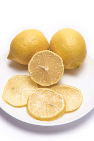Two and a half lemons and some slices on a white background taking up the whole sceneの写真素材