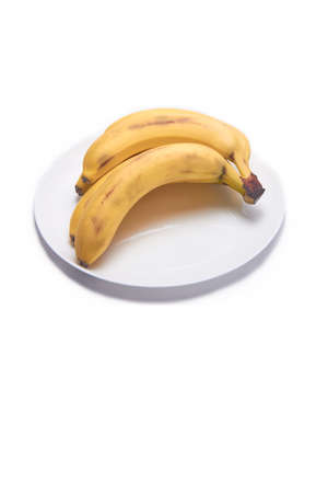 Banana bunch on white background on a plate with copy spaceの写真素材