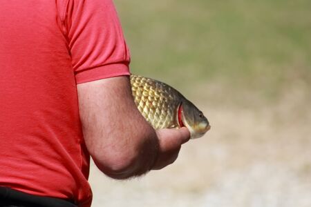 man holding a freshly caught fish in his handの写真素材