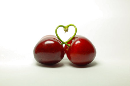cherry on a white background with a heart-shaped green leaf