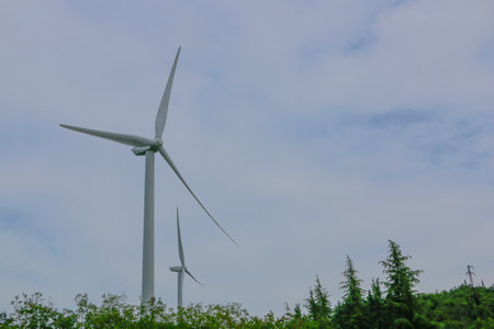 Wind turbine on green field with blue sky and white cloud background.