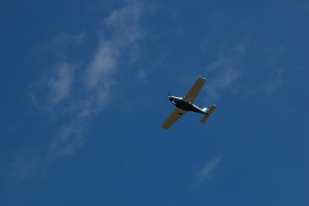 Small plane flying in the blue sky with white clouds in the background