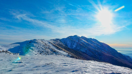 Winter mountains panorama with snow covered slopes and clear blue sky in sunny day