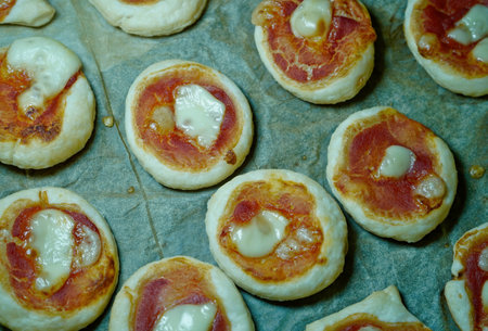 Mini pizzas with salami and mozzarella on baking paperの写真素材