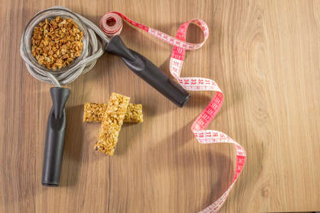 Fitness concept with dumbbells skipping rope measure tape whey protein and bananas on wooden table backgroundの写真素材