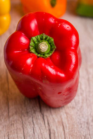 Some red, green and yellow bell peppers over a wooden surface.の写真素材