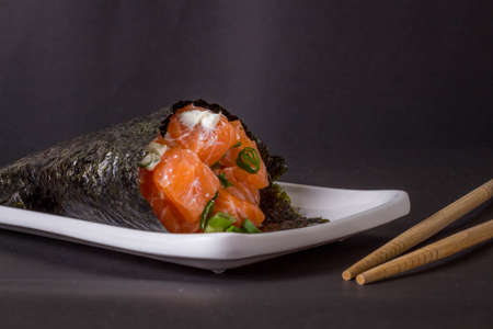 Salmon temaki sushi on white plate in black background.の写真素材