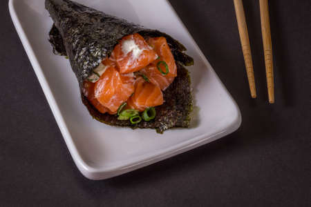 Salmon temaki sushi on white plate in black background.の写真素材