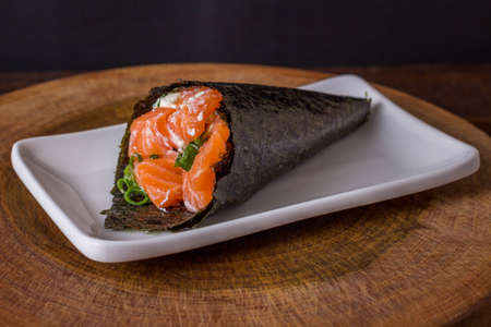 Salmon temaki sushi on white plate in black background.の写真素材