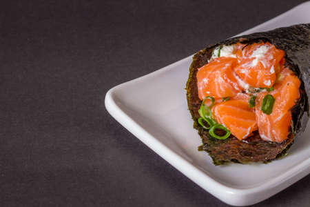 Salmon temaki sushi on white plate in black background.の写真素材