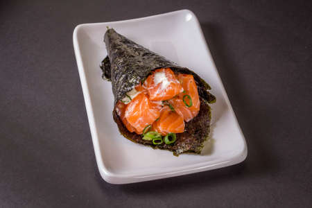 Salmon temaki sushi on white plate in black background.の写真素材