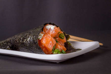 Salmon temaki sushi on white plate in black background.の写真素材