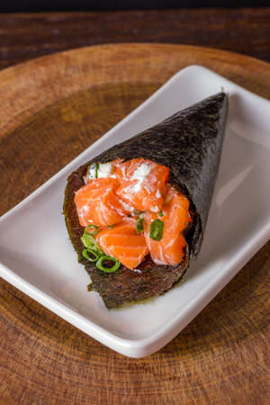 Salmon temaki sushi on white plate in black background.の写真素材