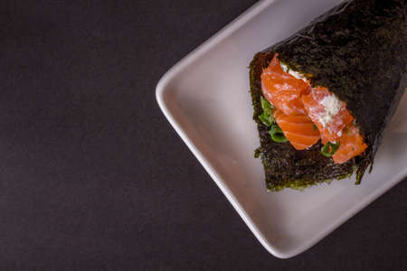 Salmon temaki sushi on white plate in black background.の写真素材