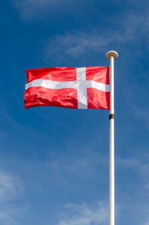 A denmark flag is floating in a blue skyの写真素材