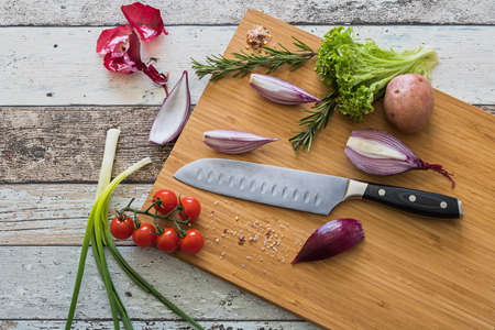 Knife with healthy food - vegetables, onion, salad, tomatoes, potato placed on a cutting board with wood background top viewの写真素材