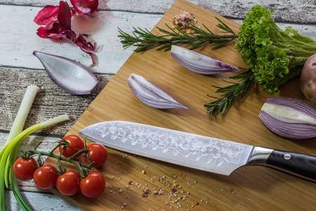 Knife with healthy food - vegetables, onion, salad, tomatoes, potato placed on a cutting board with wood background top viewの写真素材