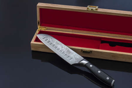 Santoku Kitchen Knife with Elegant Wood Box on Black Reflective Surfaceの写真素材