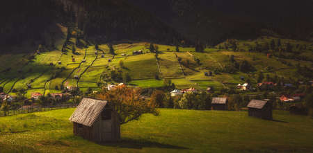 Panorama view of a mountain village at sunset. Household with meadows and farmlandの写真素材