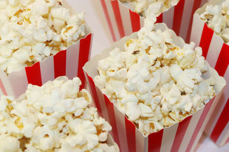 A bucket with popcorn sitting on top of a table. High quality photo. Basket with popcorn on a white background. Popcorn on a white background with place for text. Watching a movie with popcoの写真素材