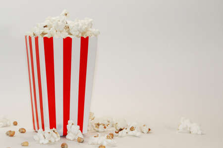 A bucket with popcorn sitting on top of a table. High quality photo. Basket with popcorn on a white background. Popcorn on a white background with place for text. Watching a movie with popcoの写真素材