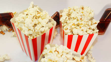 A bucket with popcorn sitting on top of a table. High quality photo. Basket with popcorn on a white background. Popcorn on a white background with place for text. Watching a movie with popcoの写真素材
