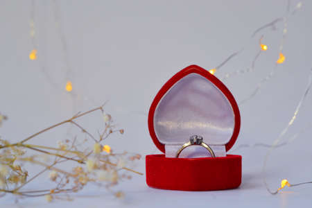 Wedding ring in a red box. Valentines Day. Valentines day gift. Layout for Valentines day with ring and roses. Love background with place for textの写真素材