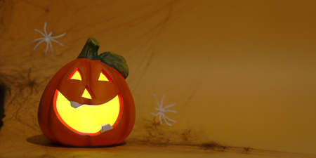 Halloween pumpkin with glowing eyes. Cheerful halloween pumpkin on an orange background. Halloween background with place for text. Nhe day of the Dead. Autumn holidayの写真素材