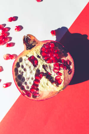 red vibrant pomegranate on multi colored trendy background, minimal summer concept healthyの写真素材