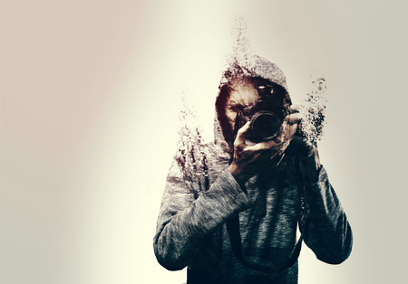 Abstract self portrait of a photographer holding a DSLR camera shattered into pieces. isolatedの写真素材