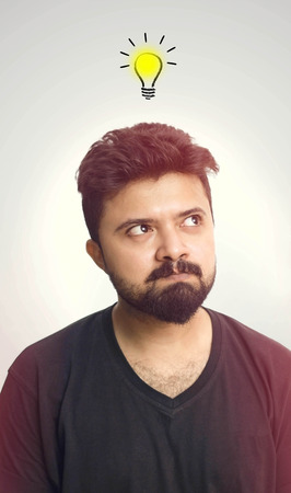 Young Men Wearing Black T Shirt Looking Up And Thinking - Ideas bulb symbol over head. Isolated On Whiteの写真素材