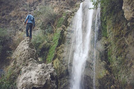 Traveler standing on a rock near waterfall, Kashmir, Pakistanの写真素材