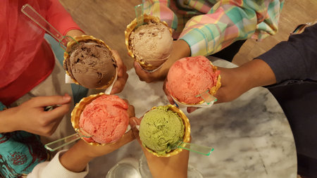 Top view of children's hands holding ice cream cones in the cafeの写真素材