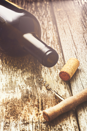 Bottle of red wine with a corkscrew and corks. On a wooden table.の写真素材