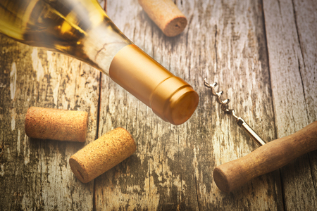 Glass bottle of wine with corkscrew on a wooden table backgroundの写真素材