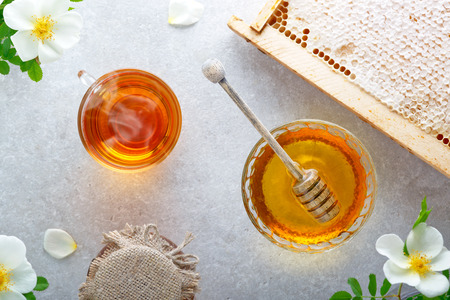 Honey background. Sweet honey in the glass jar, honey comb and fresh tea on the table. Top view.の写真素材