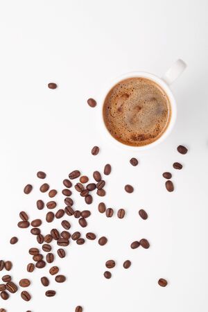 Coffee in a white cup and coffee beans on the table. White background. Top view.の写真素材