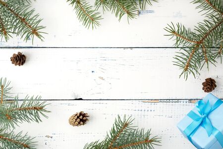 Christmas composition. Christmas gift, pine cones, fir branches on wooden white background. Flat lay, top view, copy spaceの写真素材