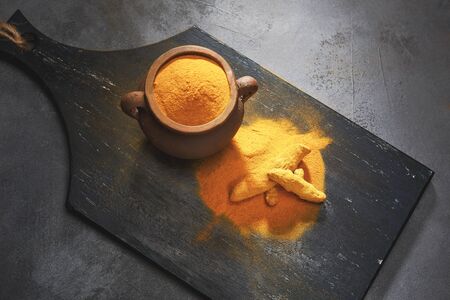 Turmeric powder and fresh turmeric on wooden background. Dark background. Top view.