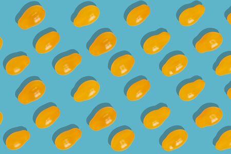 Colorful pattern of yellow tomatoes on a green background. From top view
