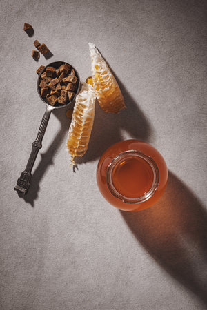 Honey background. Honey in a glass jar, honeycomb and propolis in an iron spoon. Light gray background.の写真素材