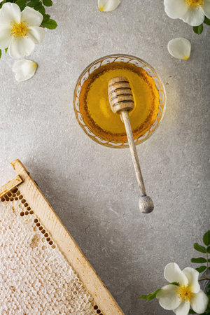 Honey background. Sweet honey in the comb, glass jar and a spoon for honey on the table. Light...