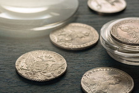 Numismatics. Old collectible coins made of silver on a wooden table. Dark background.