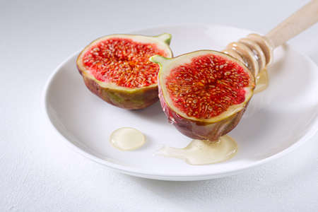 figs cut into pieces and drizzled with honey on a white plate. vitamin organic healthy foodの写真素材