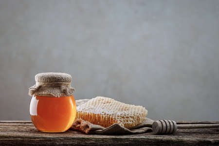 Honey background. Sweet honey in the comb, glass jar. On wooden backgroundの写真素材