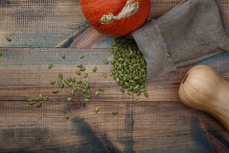 Pumpkins and pumpkin seeds on a wooden table. Top view.の写真素材