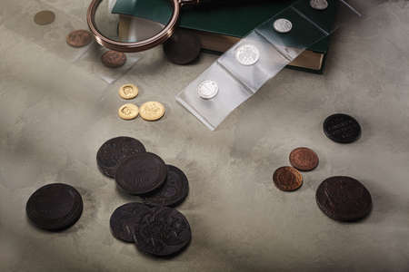 Numismatics. Old collectible coins on a wooden table. Dark background.の写真素材