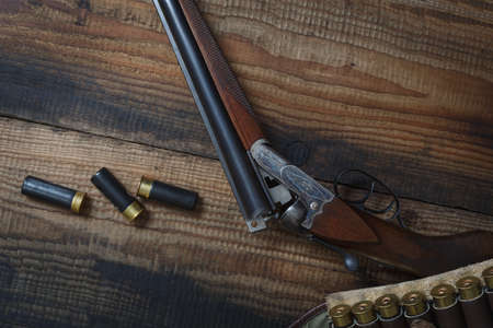 Hunting rifle and hunting accessories on the table. Vintage hunting gun with cartridges on wooden background. top view.の写真素材